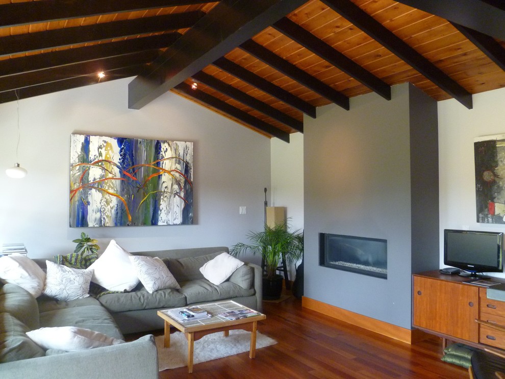 Diseño de sala de estar contemporánea con paredes blancas, suelo de madera oscura, chimenea lineal y televisor independiente