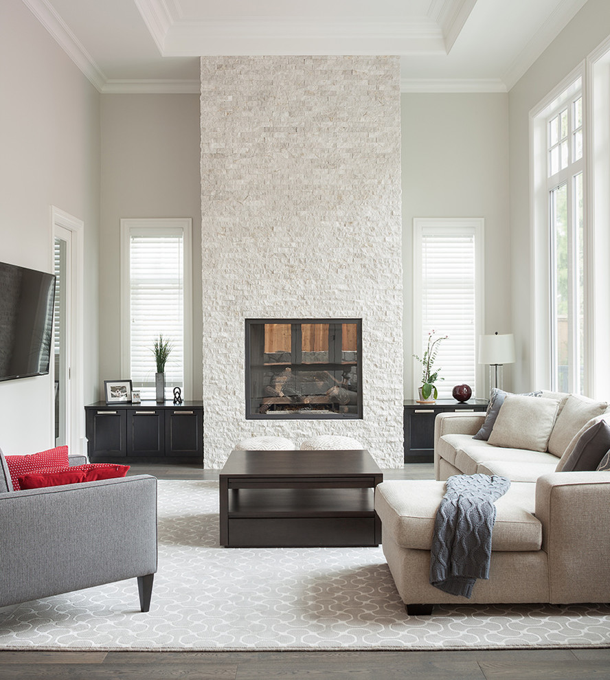 Inspiration for a large traditional enclosed games room in Vancouver with beige walls, medium hardwood flooring, a wall mounted tv, a standard fireplace, a stone fireplace surround, brown floors and feature lighting.