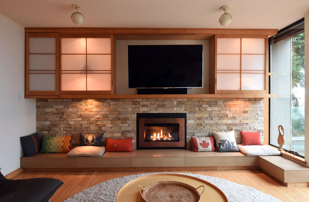 バンクーバーにある高級な中くらいなコンテンポラリースタイルのおしゃれな独立型ファミリールーム (白い壁、竹フローリング、標準型暖炉、石材の暖炉まわり、埋込式メディアウォール、ベージュの床) の写真