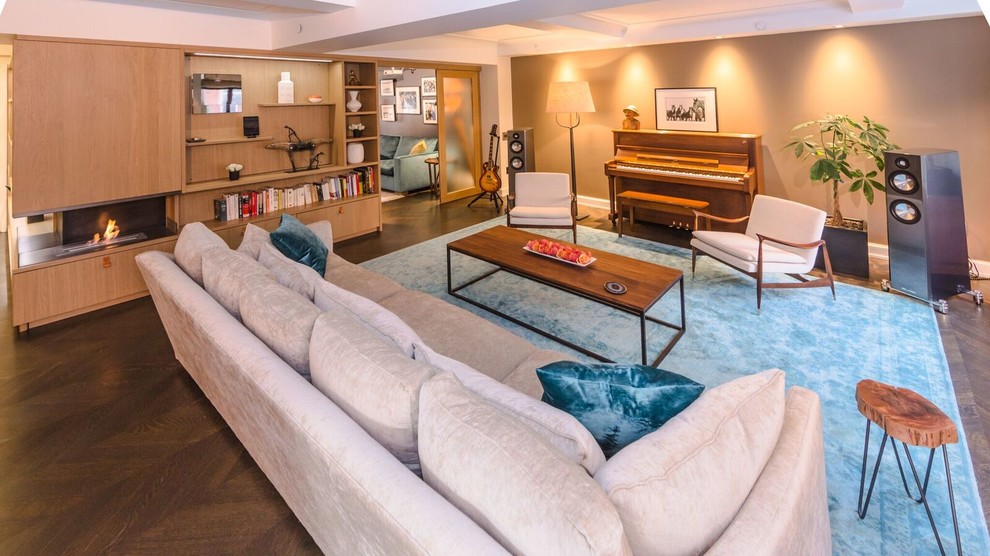 Modelo de sala de estar con rincón musical abierta actual grande con paredes beige, suelo de madera oscura y pared multimedia