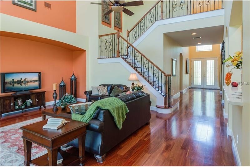 Mittelgroßes, Offenes Klassisches Wohnzimmer mit beiger Wandfarbe, dunklem Holzboden und freistehendem TV in Tampa