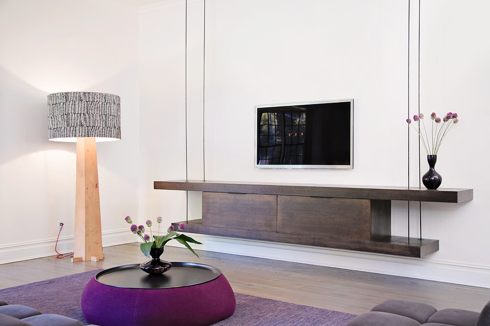 Example of a trendy light wood floor family room design in New York with white walls and a wall-mounted tv