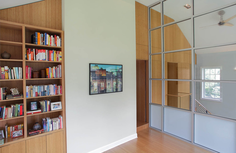 Modern inredning av ett allrum, med ett bibliotek, grå väggar och ljust trägolv