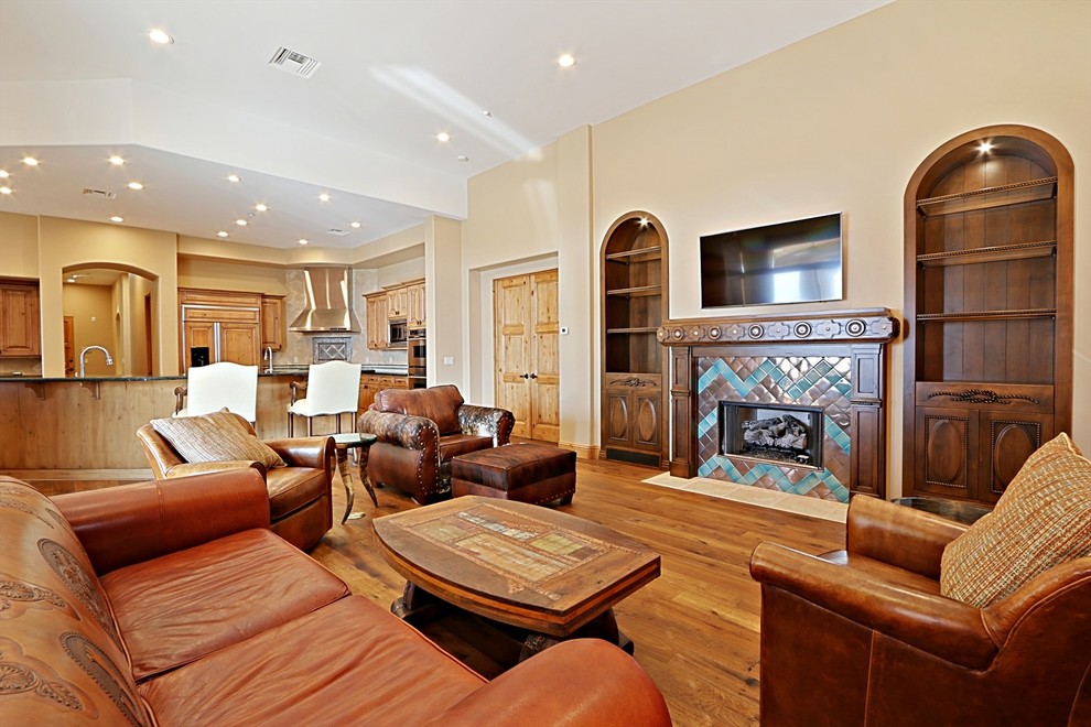 Foto de sala de estar abierta de estilo americano grande con paredes beige, suelo de madera clara, todas las chimeneas, marco de chimenea de madera y televisor colgado en la pared
