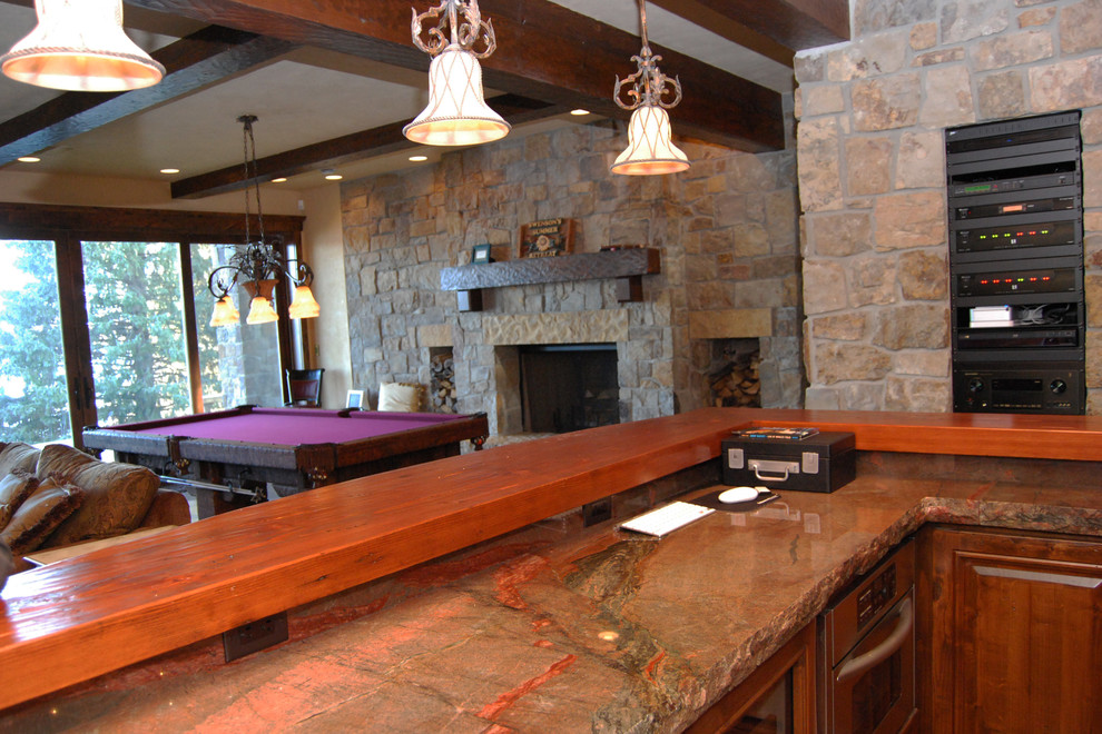 Imagen de sala de estar con barra de bar abierta rústica grande con paredes beige, suelo de madera en tonos medios, todas las chimeneas y marco de chimenea de piedra
