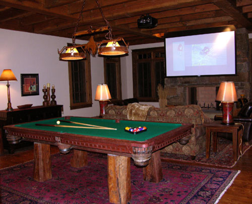 Foto di un ampio soggiorno rustico aperto con sala giochi, pareti beige, parquet scuro, camino classico, cornice del camino in pietra e TV a parete
