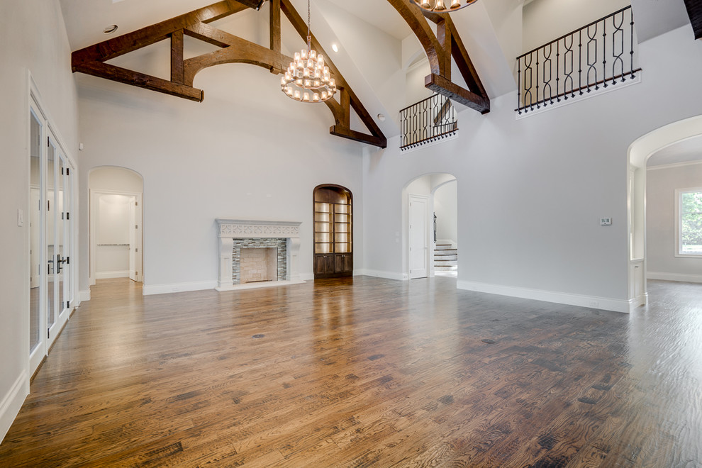 Großes, Abgetrenntes Klassisches Wohnzimmer mit Kaminumrandung aus Stein, weißer Wandfarbe, braunem Holzboden und Kamin in Dallas