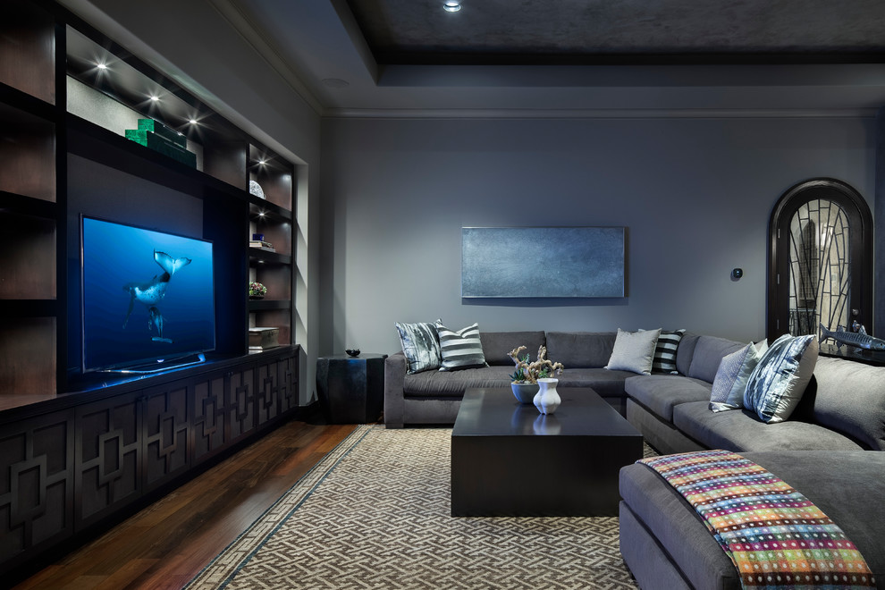 Cette photo montre une grande salle de séjour chic ouverte avec un mur gris, un sol en bois brun, un téléviseur indépendant et un sol marron.