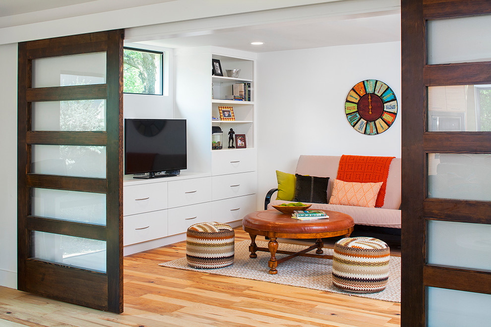 Inspiration for a medium sized contemporary enclosed games room in Austin with white walls, medium hardwood flooring and a built-in media unit.