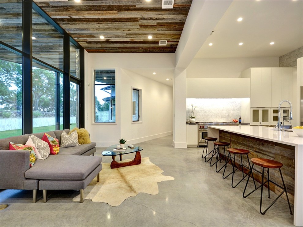 На фото: открытая гостиная комната среднего размера в стиле фьюжн с белыми стенами и бетонным полом без камина, телевизора