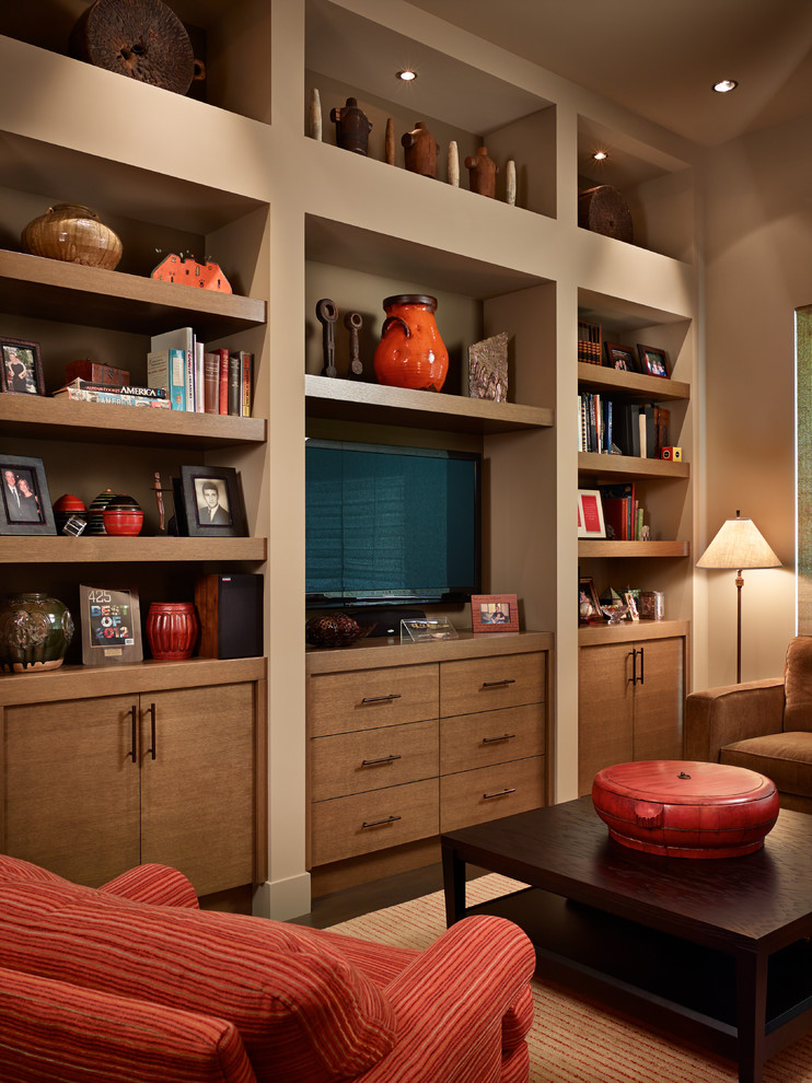 Modelo de sala de estar con biblioteca cerrada clásica de tamaño medio sin chimenea con paredes beige, suelo de madera oscura, pared multimedia y suelo marrón