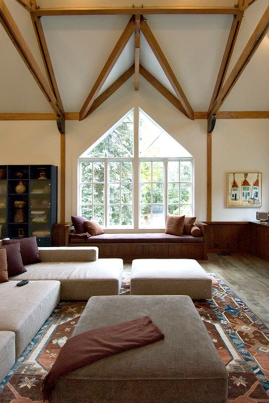 Cette image montre une grande salle de séjour minimaliste ouverte avec un mur blanc, un sol en bois brun, une cheminée standard, un manteau de cheminée en pierre et un téléviseur fixé au mur.