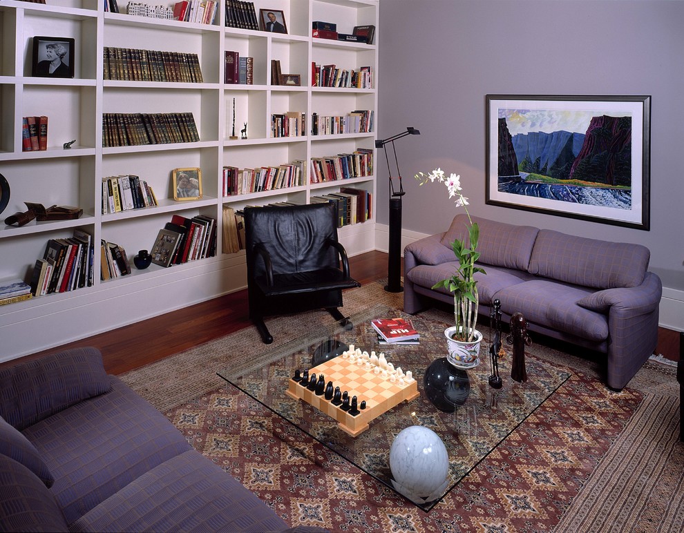 Cette image montre une salle de séjour traditionnelle de taille moyenne et fermée avec une bibliothèque ou un coin lecture, un mur violet, parquet foncé, aucune cheminée, aucun téléviseur et un sol marron.