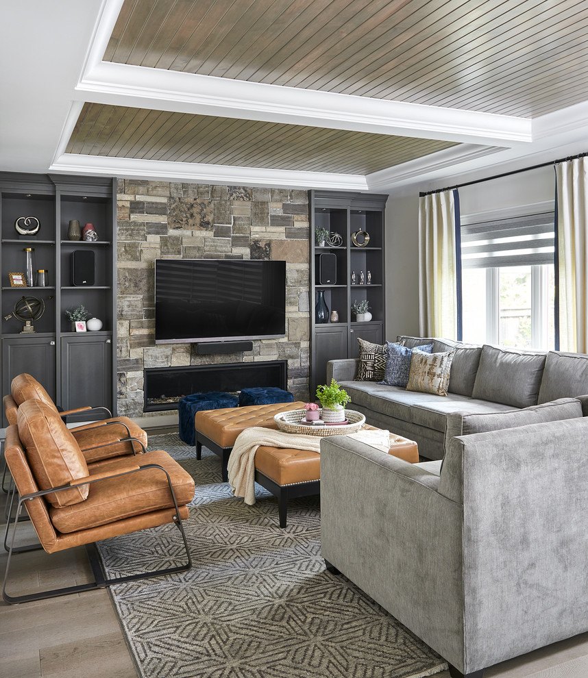 Modelo de sala de estar abierta clásica renovada grande con suelo de madera clara, chimenea lineal, marco de chimenea de piedra, televisor colgado en la pared, suelo beige y alfombra