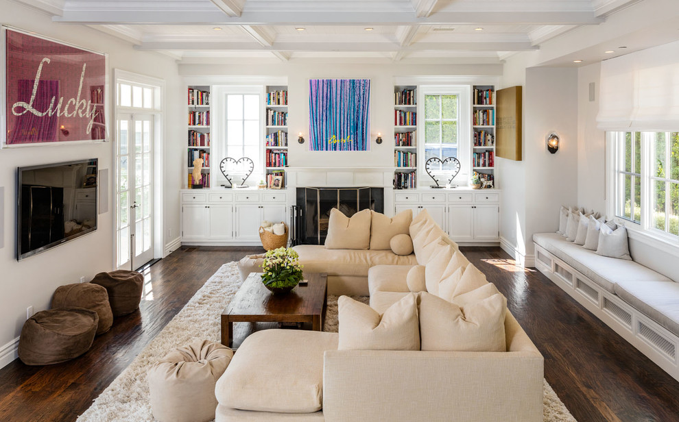 Example of a transitional dark wood floor and brown floor family room design in Los Angeles with white walls, a standard fireplace and a wall-mounted tv