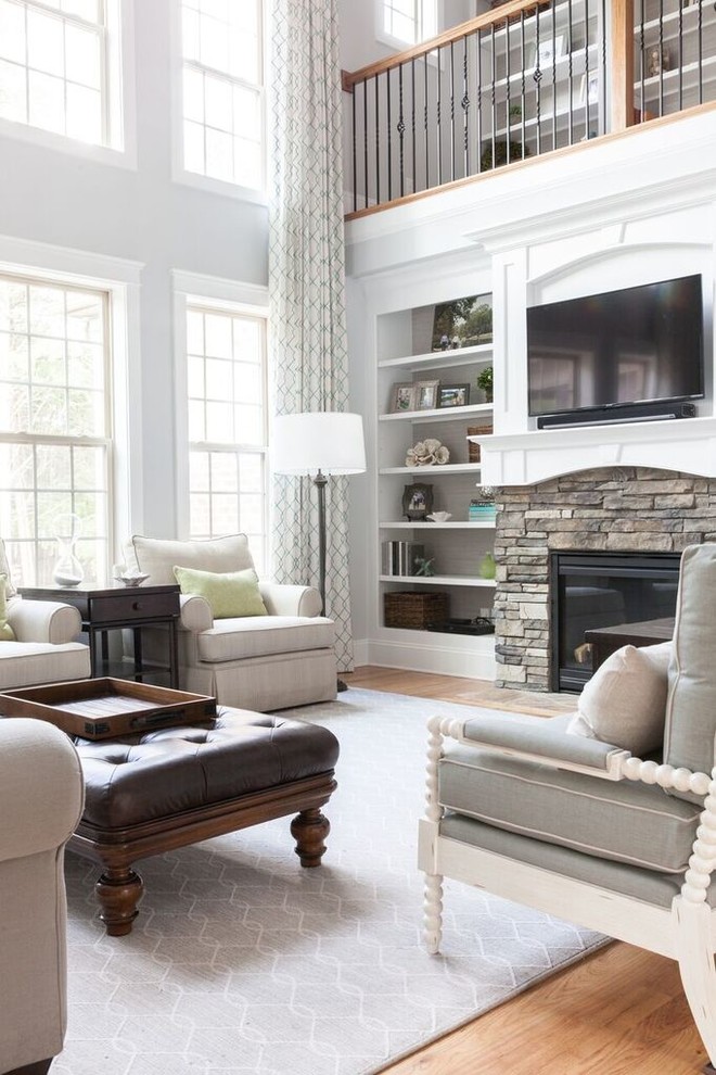 Großes, Offenes Klassisches Wohnzimmer mit grauer Wandfarbe, braunem Holzboden, Kamin, Kaminumrandung aus Stein und TV-Wand in Charlotte