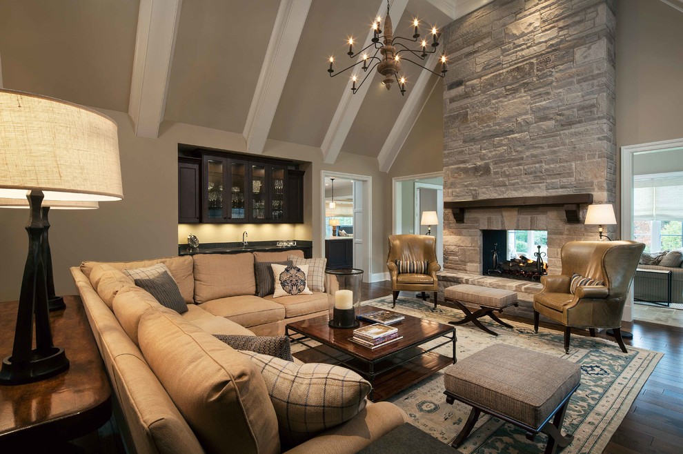 Inspiration for a mid-sized transitional open concept dark wood floor and brown floor family room remodel in Chicago with a bar, beige walls, a two-sided fireplace, a stone fireplace and no tv