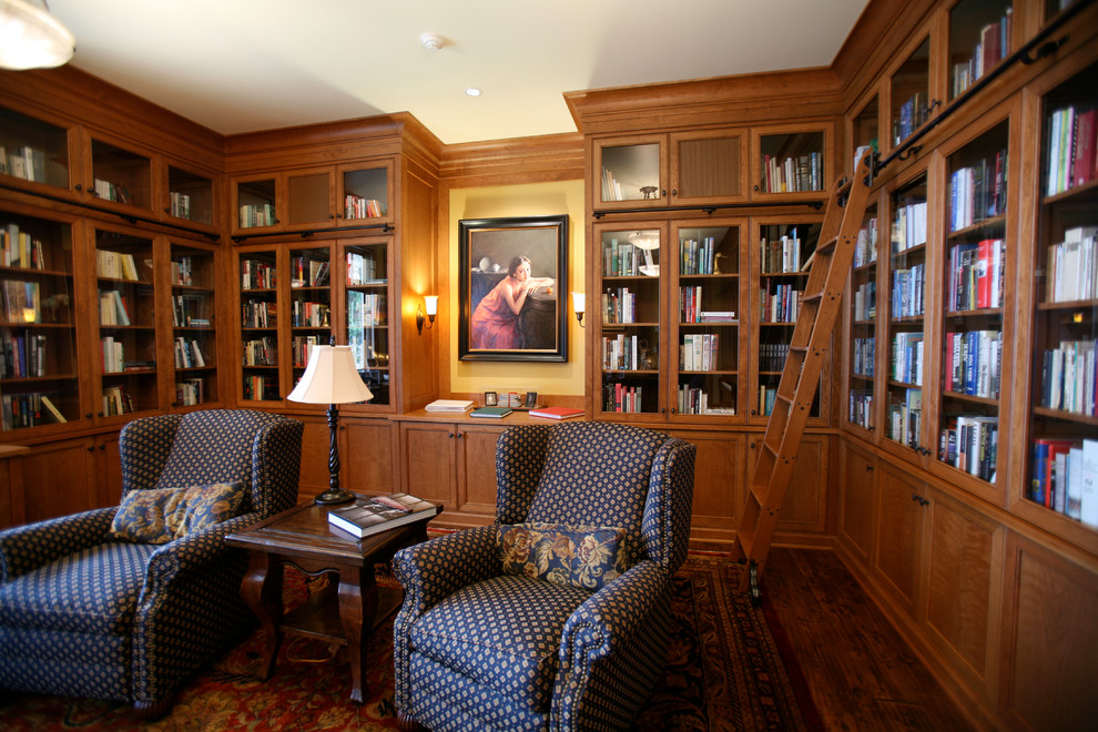 Modelo de sala de estar con biblioteca cerrada tradicional grande sin chimenea y televisor con paredes amarillas y suelo de madera oscura