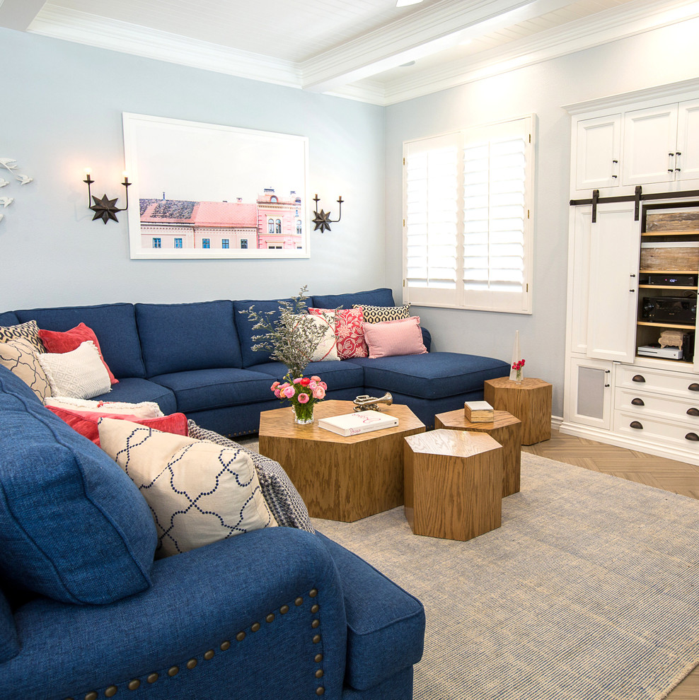 ロサンゼルスにあるお手頃価格の広いトランジショナルスタイルのおしゃれなオープンリビング (青い壁、セラミックタイルの床、コーナー設置型暖炉、木材の暖炉まわり、壁掛け型テレビ、茶色い床) の写真