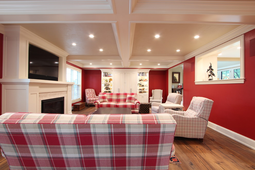 Aménagement d'une grande salle de séjour classique fermée avec un mur rouge, un sol en bois brun, une cheminée standard, un manteau de cheminée en carrelage, un téléviseur fixé au mur et un sol marron.
