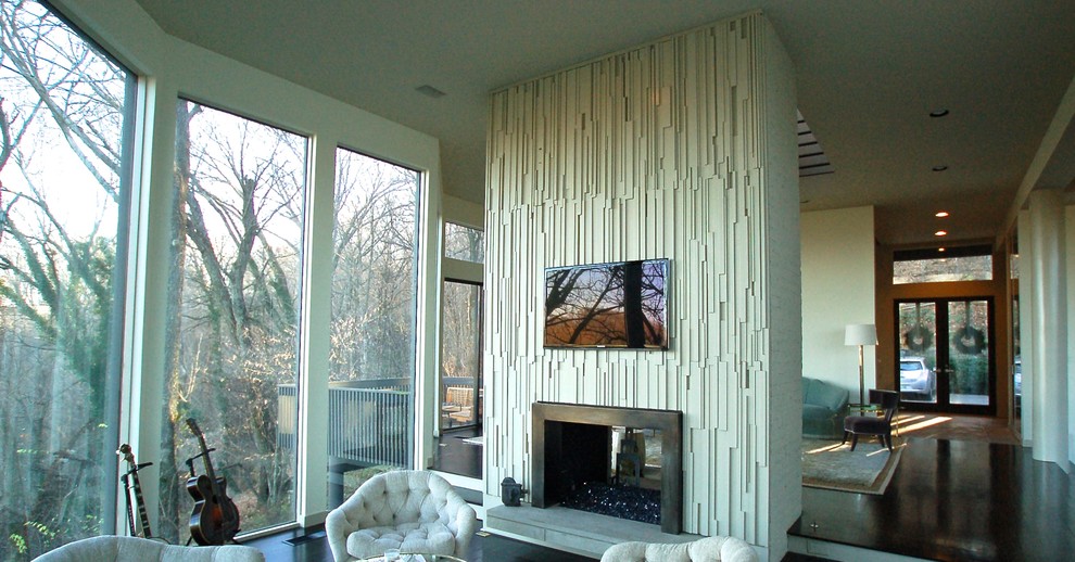 Aménagement d'une grande salle de séjour moderne ouverte avec un mur blanc, parquet foncé, une cheminée double-face, un manteau de cheminée en bois et un téléviseur fixé au mur.