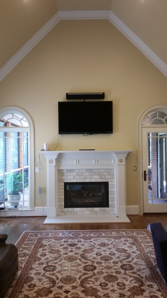 Cette photo montre une salle de séjour moderne avec un mur beige, parquet foncé, une cheminée standard, un manteau de cheminée en carrelage et un téléviseur fixé au mur.