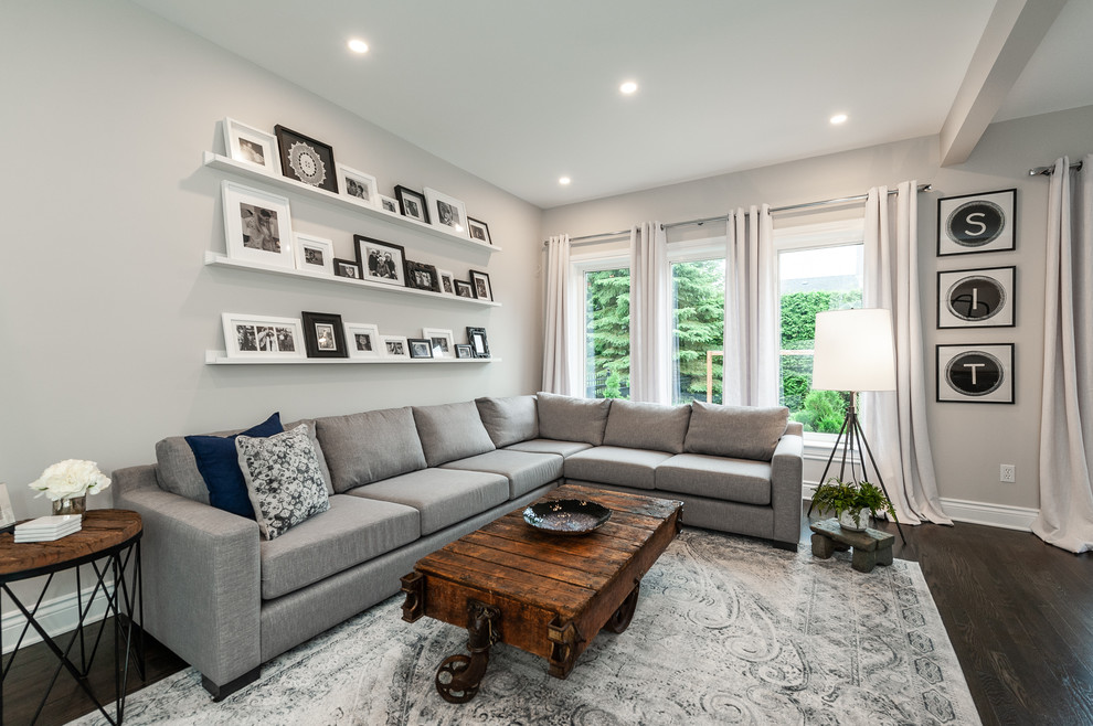 Ejemplo de sala de estar abierta contemporánea de tamaño medio con paredes grises, suelo de madera oscura, suelo marrón y televisor colgado en la pared