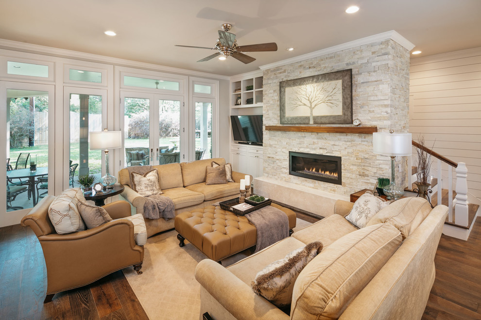 Inspiration for a large transitional open concept medium tone wood floor and brown floor family room remodel in Houston with gray walls, a ribbon fireplace, a plaster fireplace and a wall-mounted tv
