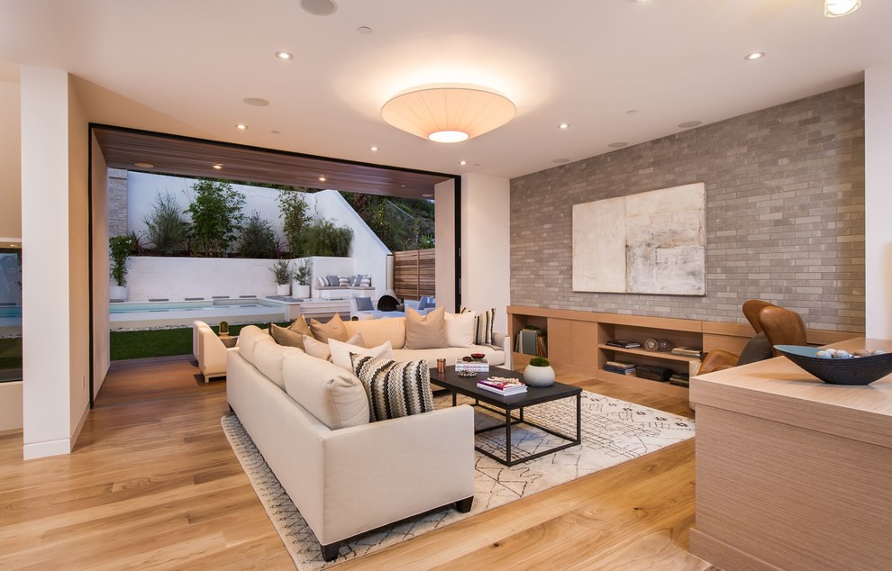 Example of a huge trendy open concept light wood floor family room library design in Los Angeles with gray walls and a wall-mounted tv