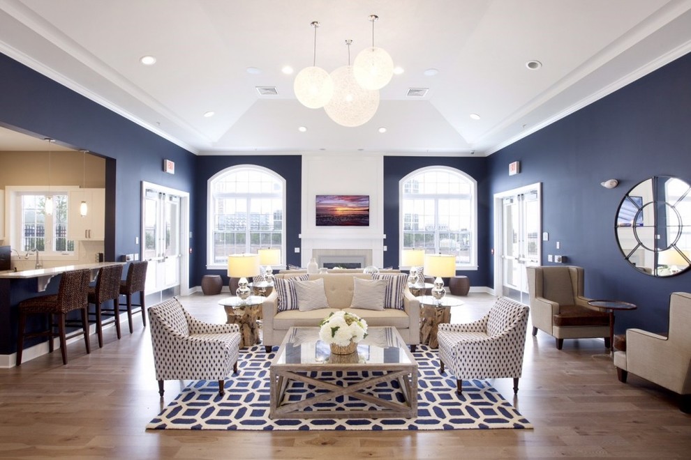 Cette photo montre une grande salle de séjour tendance ouverte avec un mur bleu, parquet clair, une cheminée standard, un téléviseur fixé au mur, un manteau de cheminée en carrelage, un sol beige et éclairage.