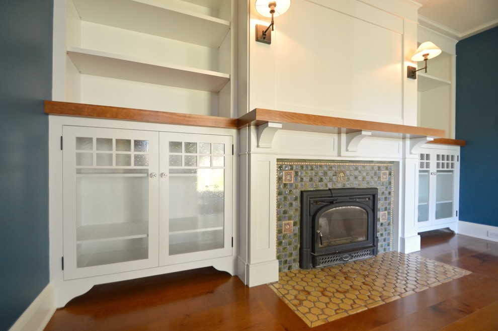 Cette image montre une salle de séjour traditionnelle de taille moyenne et fermée avec un mur bleu, un sol en bois brun, une cheminée standard, un manteau de cheminée en carrelage, aucun téléviseur et un sol marron.