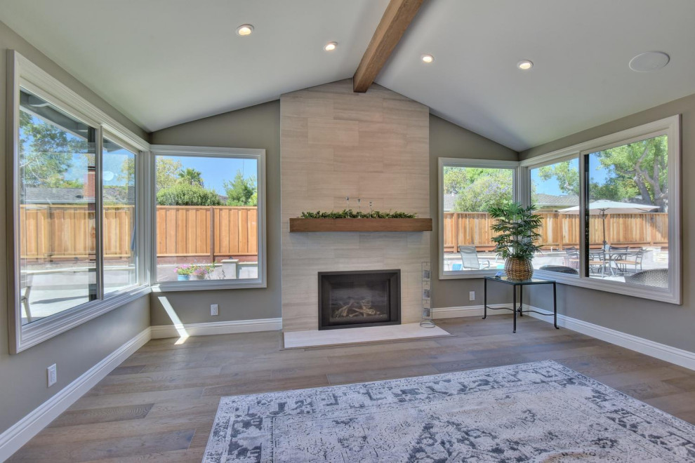 Mid-sized trendy open concept laminate floor and gray floor family room photo in San Francisco with gray walls, a standard fireplace, a tile fireplace and a wall-mounted tv