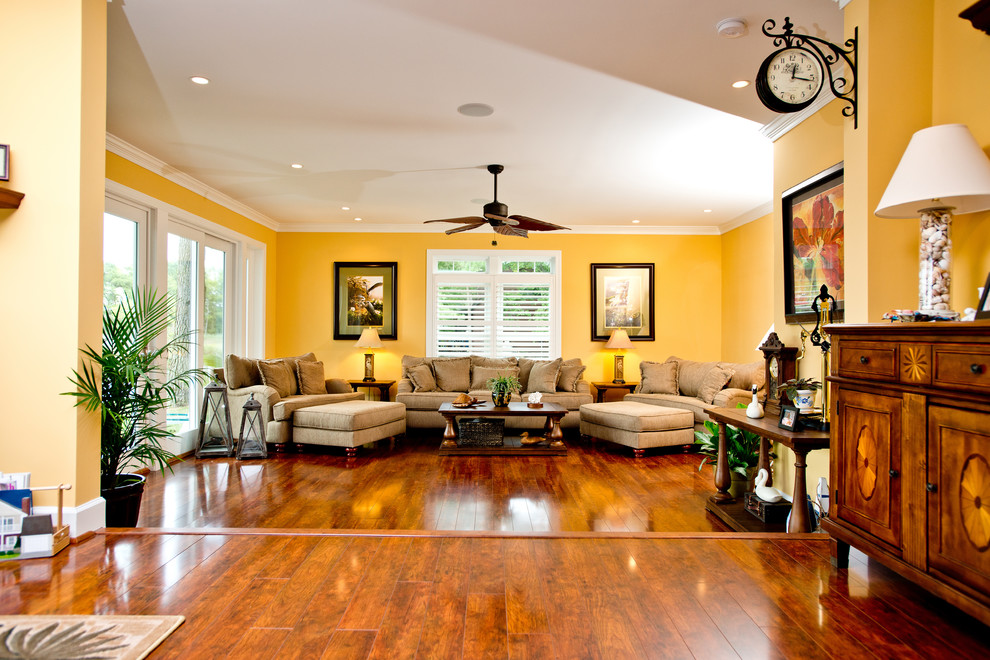 Foto di un grande soggiorno classico aperto con pareti gialle e pavimento in legno massello medio