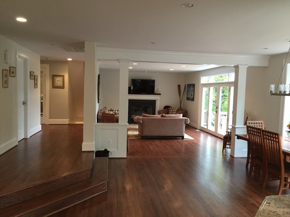 Example of a large transitional open concept medium tone wood floor family room design in DC Metro with white walls, a standard fireplace, a wood fireplace surround and a wall-mounted tv