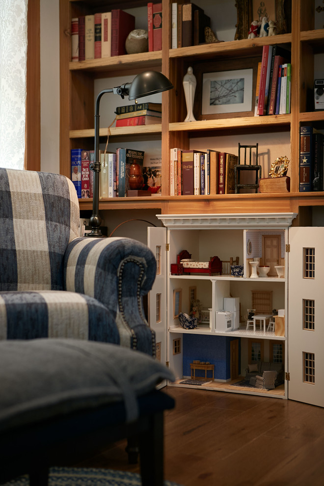 Cette image montre une salle de séjour mansardée ou avec mezzanine traditionnelle de taille moyenne avec une bibliothèque ou un coin lecture, un mur blanc, parquet foncé et un sol marron.