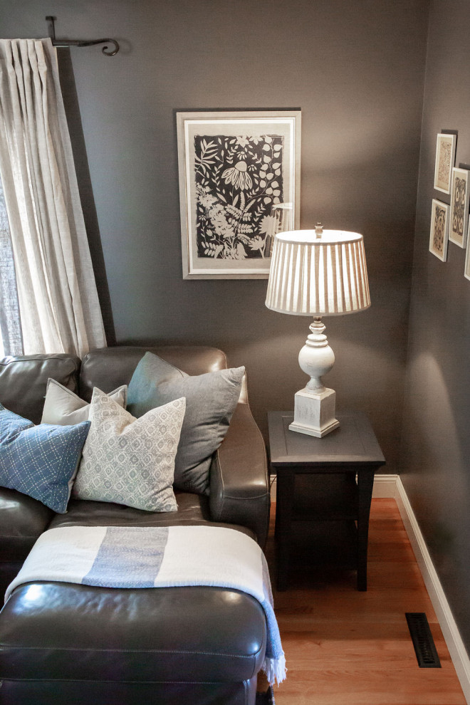 Cette image montre une salle de séjour traditionnelle de taille moyenne et fermée avec un mur bleu, un sol en bois brun, un téléviseur fixé au mur et un sol marron.