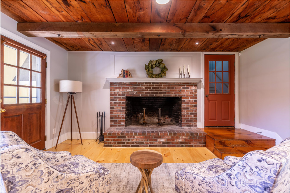 Offenes Landhaus Wohnzimmer mit braunem Holzboden, Kamin, Kaminumrandung aus Backstein und Holzdecke in Boston