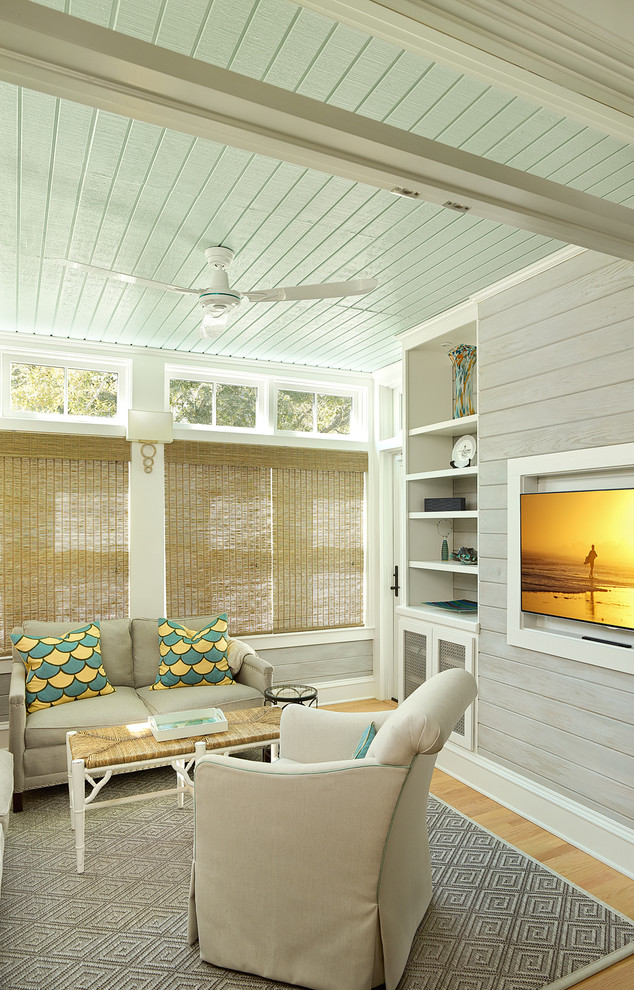 Imagen de sala de estar costera con paredes grises, suelo de madera clara, televisor colgado en la pared y alfombra