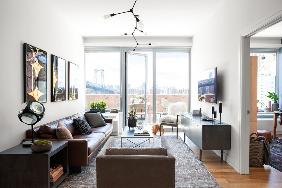 Industrial Wohnzimmer ohne Kamin mit weißer Wandfarbe, hellem Holzboden und TV-Wand in New York