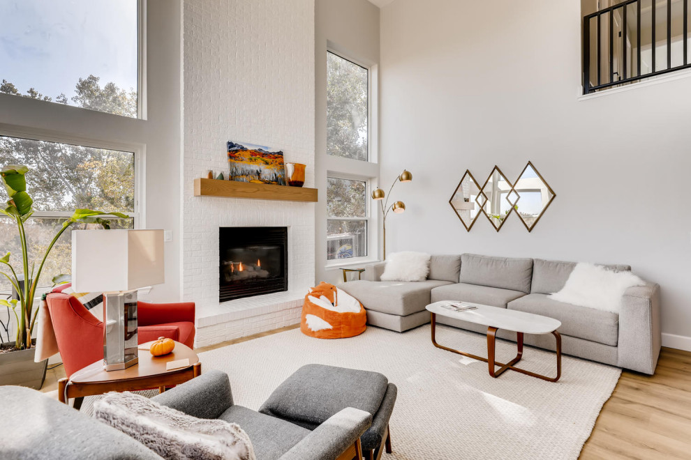 Großes, Offenes Modernes Wohnzimmer mit weißer Wandfarbe, Laminat, Kamin, Kaminumrandung aus Backstein, beigem Boden und gewölbter Decke in Denver