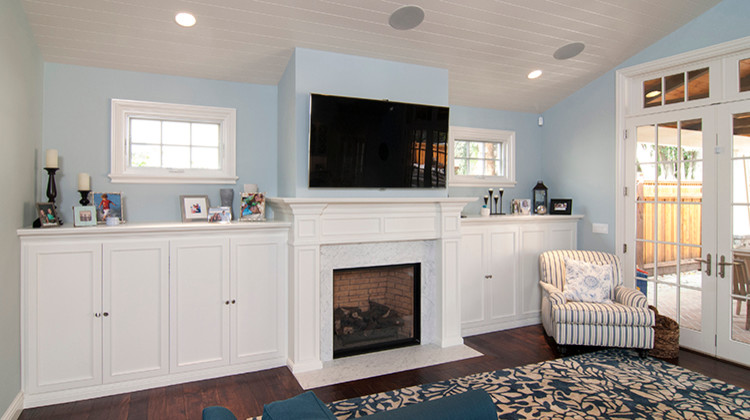 Стильный дизайн: большая открытая гостиная комната в стиле кантри с синими стенами, темным паркетным полом, стандартным камином, фасадом камина из камня и телевизором на стене - последний тренд
