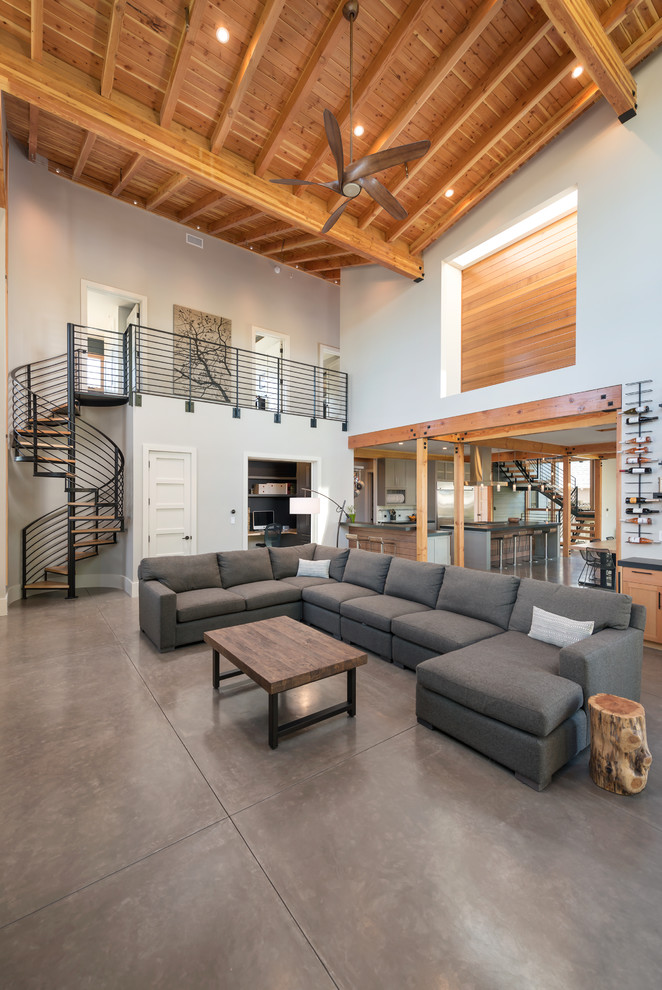 Inspiration for a large rustic open plan games room in San Francisco with grey walls, concrete flooring, a standard fireplace, a stone fireplace surround and a wall mounted tv.