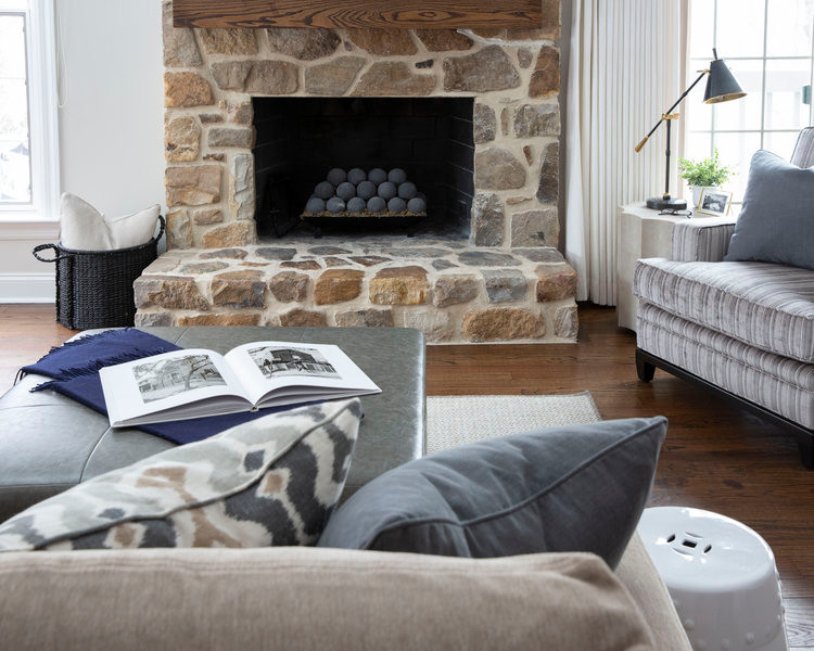 Cette image montre une salle de séjour design de taille moyenne et ouverte avec salle de jeu, un mur blanc, un sol en bois brun, une cheminée standard, un manteau de cheminée en pierre et un sol marron.