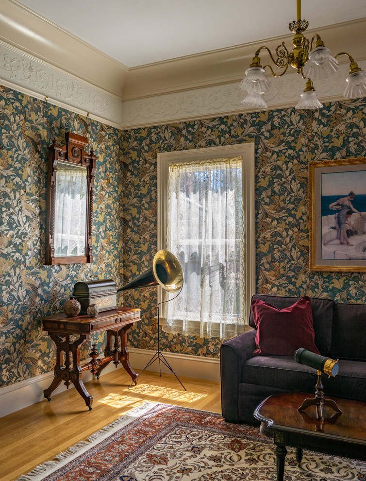 Cette photo montre une salle de séjour victorienne avec un mur multicolore, un sol en bois brun, un sol marron et canapé noir.