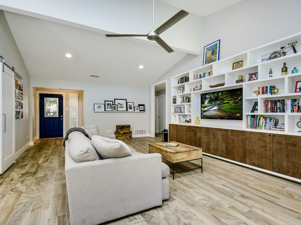 Großes, Offenes Modernes Wohnzimmer mit grauer Wandfarbe, braunem Holzboden, Multimediawand und braunem Boden in Austin