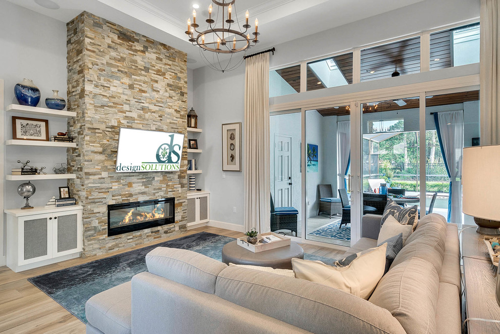 Family room - large transitional enclosed light wood floor and brown floor family room idea in Orlando with gray walls, a ribbon fireplace, a stone fireplace and a wall-mounted tv