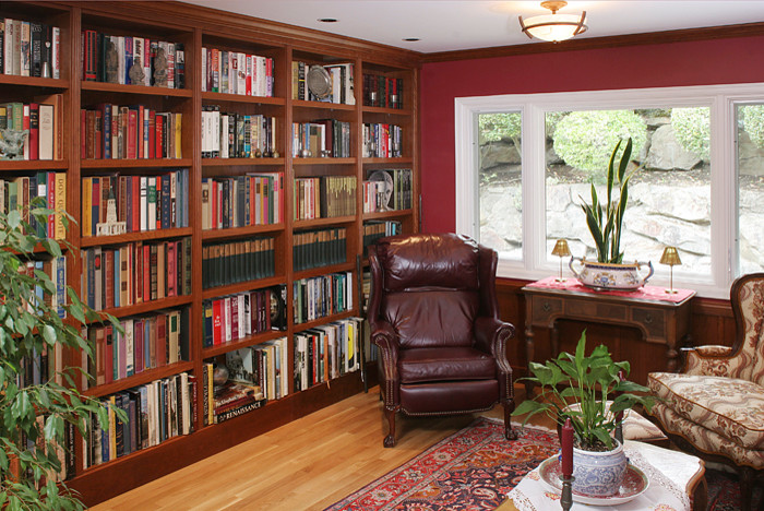 Inspiration pour une salle de séjour traditionnelle de taille moyenne et fermée avec une bibliothèque ou un coin lecture, parquet clair, un mur rouge, aucune cheminée et aucun téléviseur.
