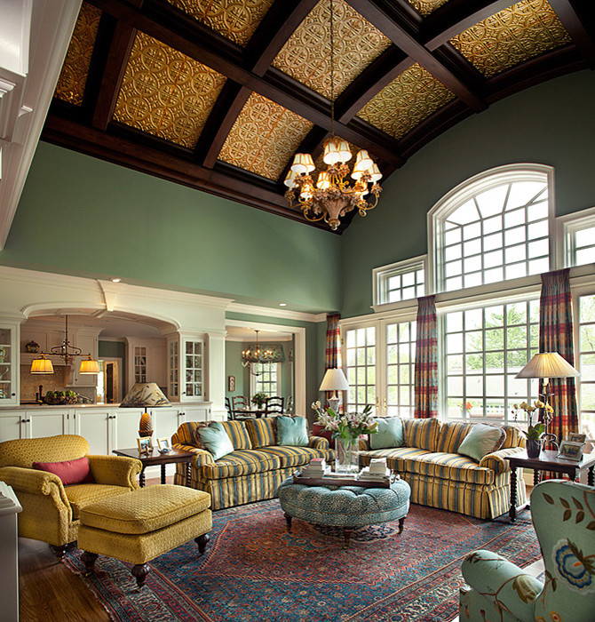 Пример оригинального дизайна: открытая гостиная комната в стиле неоклассика (современная классика) с зелеными стенами, паркетным полом среднего тона, стандартным камином, фасадом камина из плитки, телевизором на стене и коричневым полом