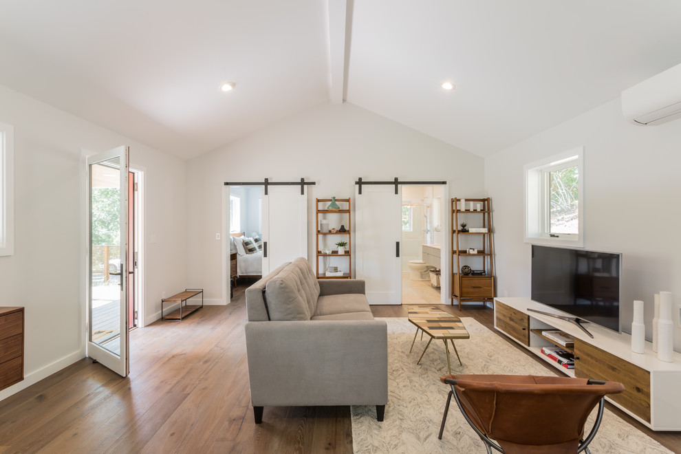 Esempio di un soggiorno minimal di medie dimensioni e aperto con pareti bianche, pavimento in legno massello medio, TV autoportante e pavimento marrone