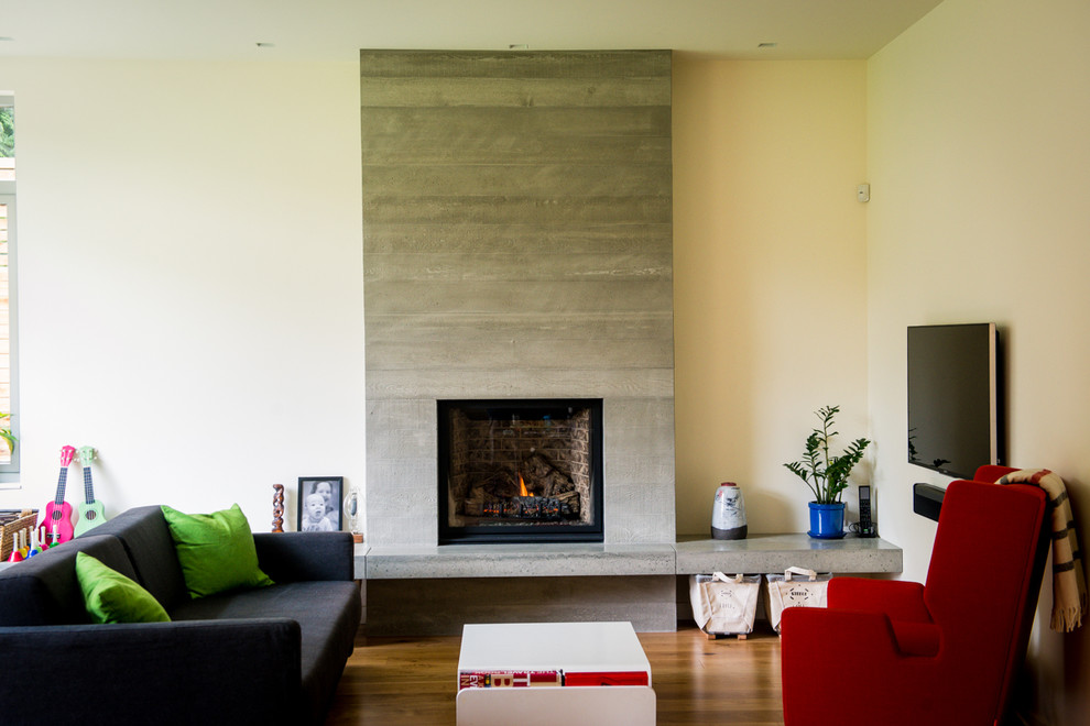Imagen de sala de estar abierta moderna grande con paredes blancas, suelo de madera en tonos medios, todas las chimeneas y marco de chimenea de hormigón